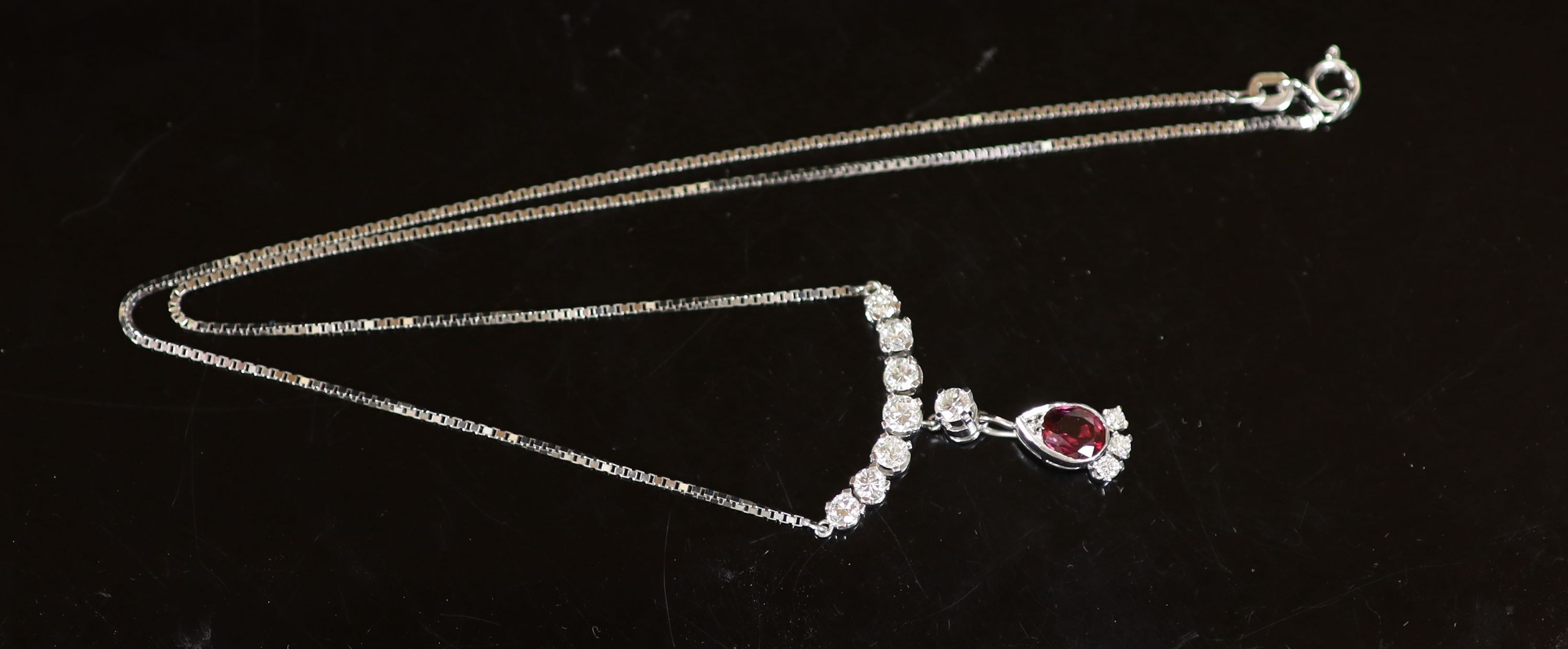 A modern Italian 18ct white gold, single stone oval cut ruby and eleven stone diamond set drop pendant necklace